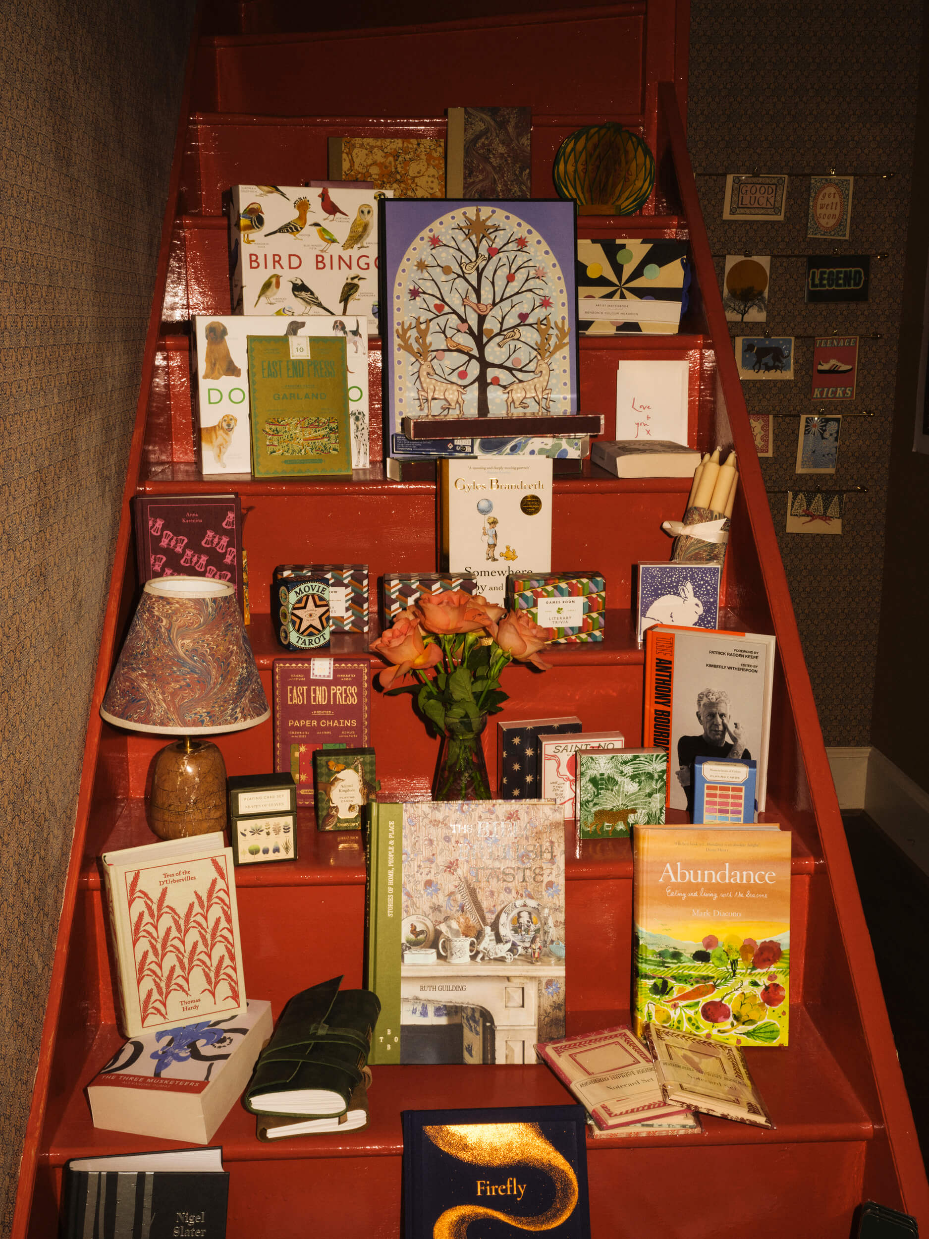 Close-up interior view of books, gifts and homewares on red stairs at Fox & King, Independent Bookshop, Tisbury.